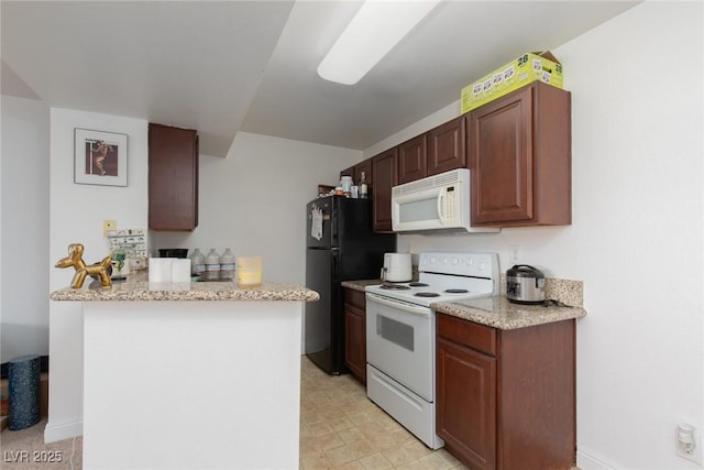 kitchen featuring white appliances, a peninsula, light stone counters, and light floors