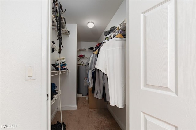 spacious closet featuring electric water heater and carpet flooring