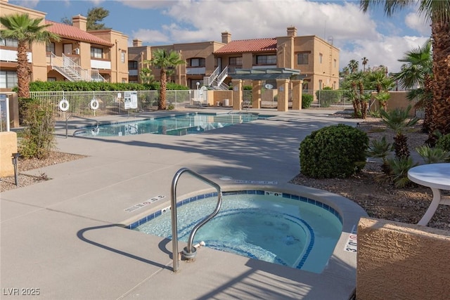 community pool with a hot tub, fence, a residential view, and a patio