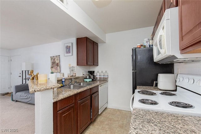 kitchen featuring white appliances, a sink, a peninsula, baseboards, and light stone counters