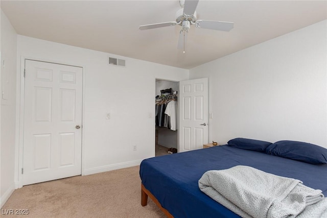 bedroom featuring light carpet, baseboards, a ceiling fan, a closet, and a spacious closet