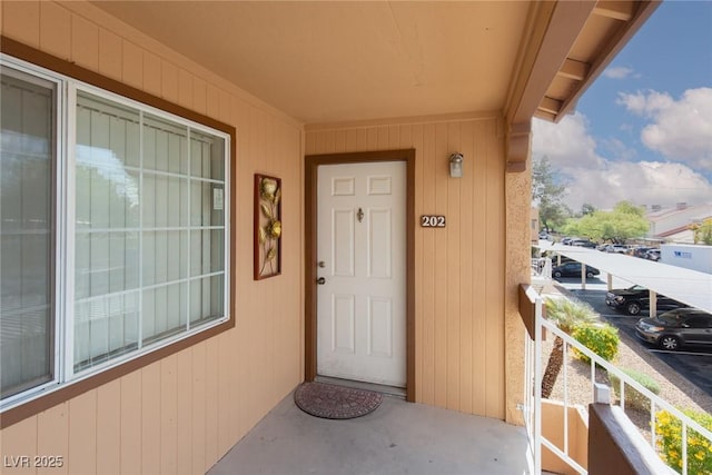 view of exterior entry featuring a balcony and uncovered parking