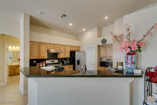 9524 Tyler Rose St, Las Vegas, NV 89178 - kitchen with stainless steel appliances, under cabinet range hood, arched walkways, decorative backsplash, and light tile patterned floors