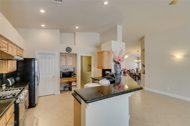 9524 Tyler Rose St, Las Vegas, NV 89178 - kitchen with stainless steel range with gas cooktop, washer and dryer, light brown cabinets, a peninsula, and vaulted ceiling