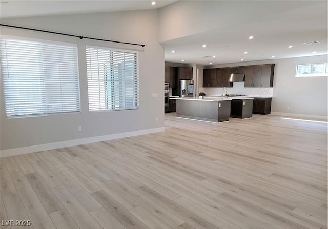 unfurnished living room with light wood-type flooring, recessed lighting, baseboards, and vaulted ceiling