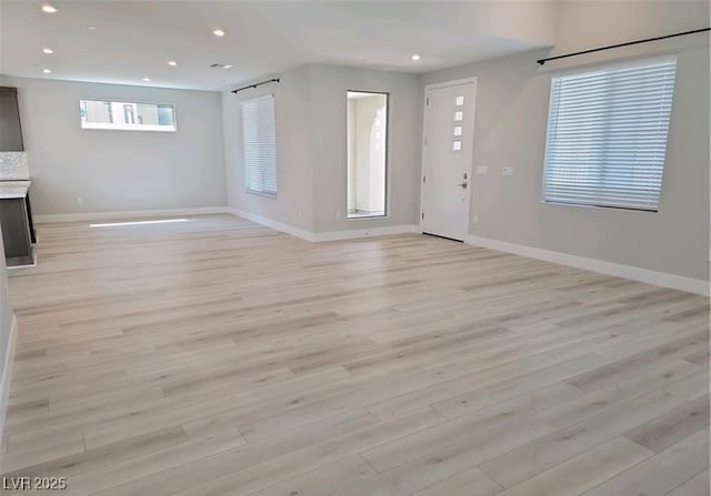 unfurnished living room featuring baseboards, light wood finished floors, and recessed lighting