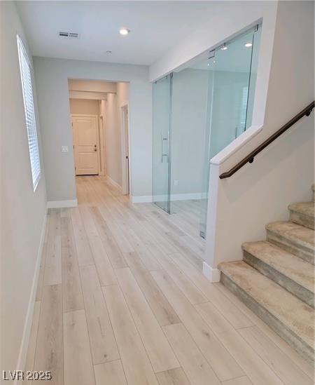 unfurnished room featuring light wood finished floors, stairway, baseboards, and recessed lighting