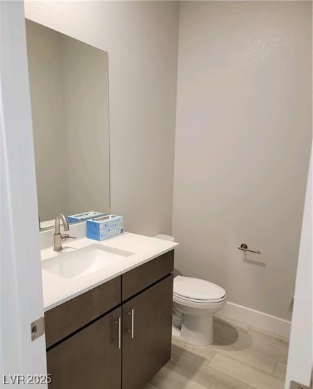 bathroom with vanity, toilet, and baseboards