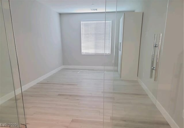 empty room featuring light wood-type flooring and baseboards