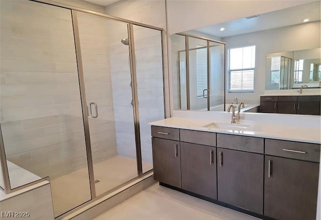bathroom featuring a stall shower, two vanities, and recessed lighting