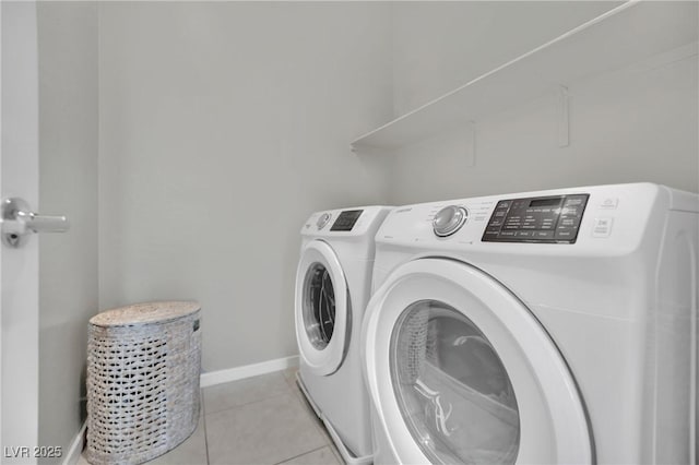 laundry area with washer and clothes dryer, baseboards, and light tile patterned floors