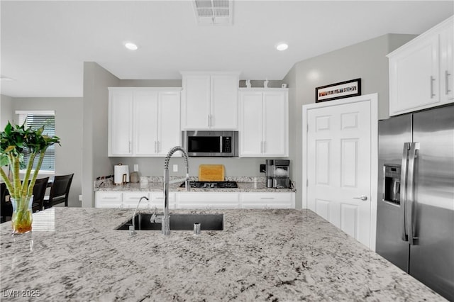 kitchen with stainless steel appliances, a sink, white cabinetry, and recessed lighting