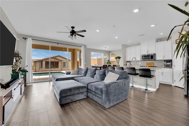 living room featuring wood finished floors, a ceiling fan, and recessed lighting