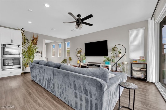 living area with wood finished floors, a ceiling fan, recessed lighting, and baseboards