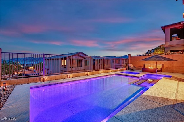 pool at dusk with a fenced backyard, a patio area, and a pool with connected hot tub