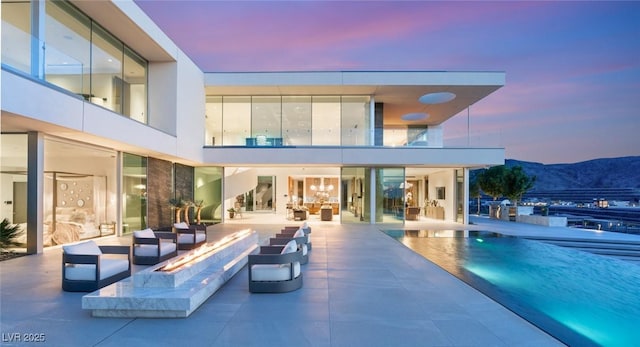 rear view of house featuring a patio, a balcony, an outdoor living space with a fire pit, and a mountain view