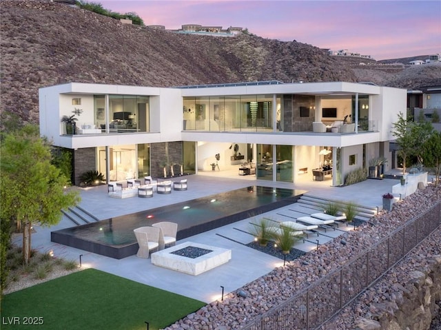 13 Rockstream Dr, Henderson, NV 89012 - back of property with a balcony, a patio area, an outdoor living space with a fire pit, an infinity pool, and stone siding