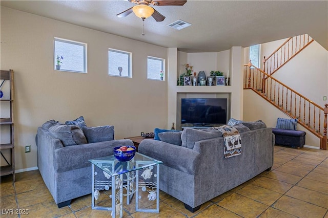 living room with ceiling fan, stairs, and baseboards