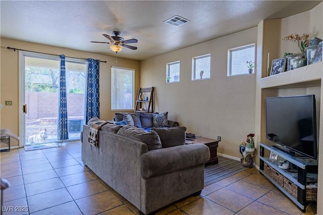 tiled living room featuring ceiling fan, a textured ceiling, and baseboards