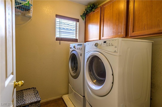 washroom with cabinet space, washing machine and clothes dryer, and baseboards