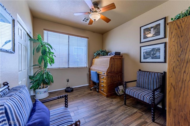 sitting room with wood finished floors, a ceiling fan, and baseboards