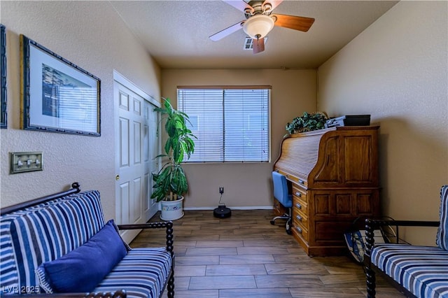 office space featuring wood finished floors, a ceiling fan, baseboards, and a textured wall