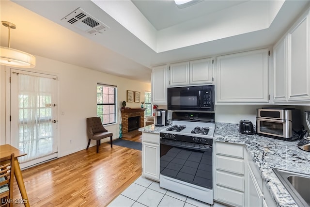5576 W Rochelle Ave Unit 27C, Las Vegas, NV 89103 - kitchen featuring gas range oven, black microwave, white cabinetry, a raised ceiling, and light stone countertops