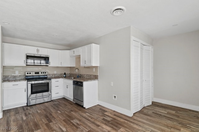 kitchen with stainless steel appliances, baseboards, dark wood-type flooring, and white cabinetry