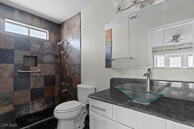 full bath featuring toilet, tiled shower, and vanity
