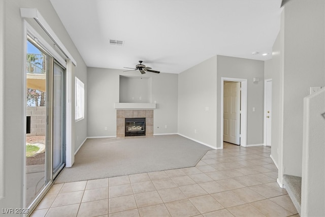 1221 Diamond Valley St, Henderson, NV 89052 - unfurnished living room with a tiled fireplace, light tile patterned floors, a ceiling fan, light colored carpet, and plenty of natural light