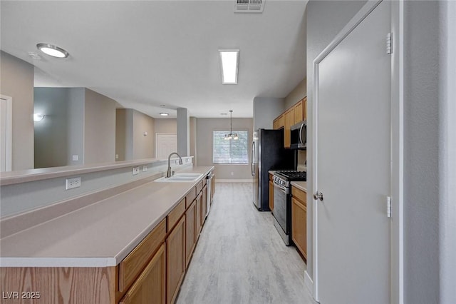 701 Peachy Canyon Cir Unit 201, Las Vegas, NV 89144 - kitchen featuring appliances with stainless steel finishes, a sink, light wood-style floors, brown cabinets, and baseboards