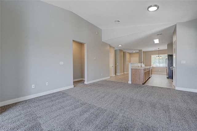 701 Peachy Canyon Cir Unit 201, Las Vegas, NV 89144 - unfurnished living room featuring vaulted ceiling, a sink, light carpet, baseboards, and a chandelier