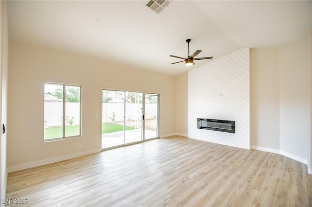 unfurnished living room with plenty of natural light, ceiling fan, a fireplace, wood finished floors, and lofted ceiling