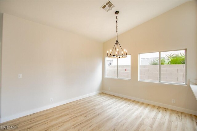 spare room with vaulted ceiling, a chandelier, wood finished floors, and baseboards