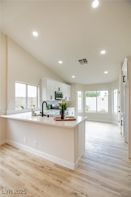 kitchen with stainless steel appliances, light wood-style flooring, white cabinets, light countertops, and recessed lighting