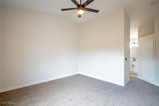 empty room featuring a ceiling fan, carpet floors, baseboards, and lofted ceiling