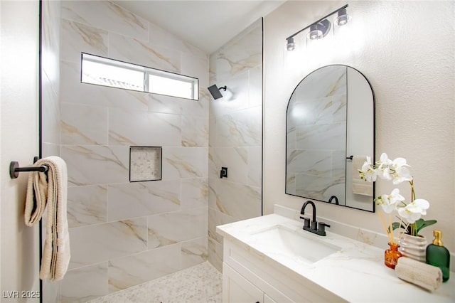 full bathroom with a tile shower, vanity, and lofted ceiling