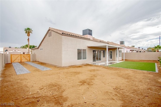 back of house with a fenced backyard, a patio area, a gate, stucco siding, and a tile roof
