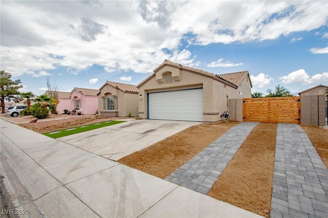 mediterranean / spanish home with a gate, driveway, stucco siding, and an attached garage