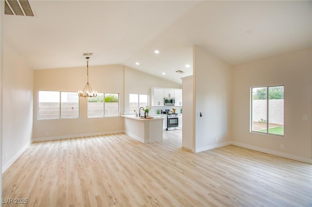 unfurnished living room featuring light wood-style flooring, vaulted ceiling, a chandelier, a sink, and baseboards