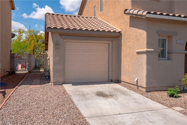 view of property exterior featuring driveway, a tiled roof, an attached garage, and stucco siding