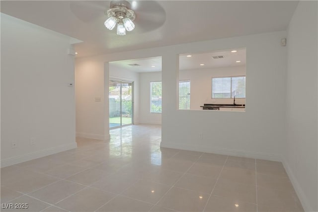 empty room featuring ceiling fan, healthy amount of natural light, baseboards, light tile patterned floors, and recessed lighting
