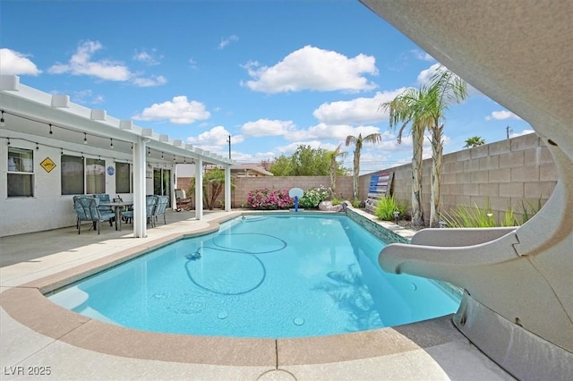 view of swimming pool with a water slide, a fenced backyard, a patio area, and outdoor dining space