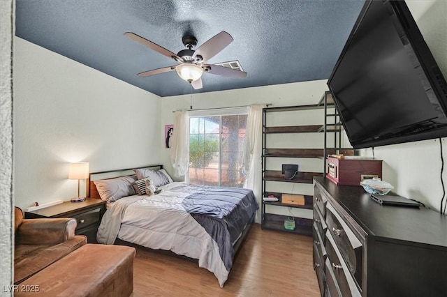 bedroom with wood finished floors, a textured ceiling, a ceiling fan, and access to exterior