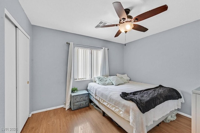bedroom with wood finished floors, a closet, baseboards, and a ceiling fan