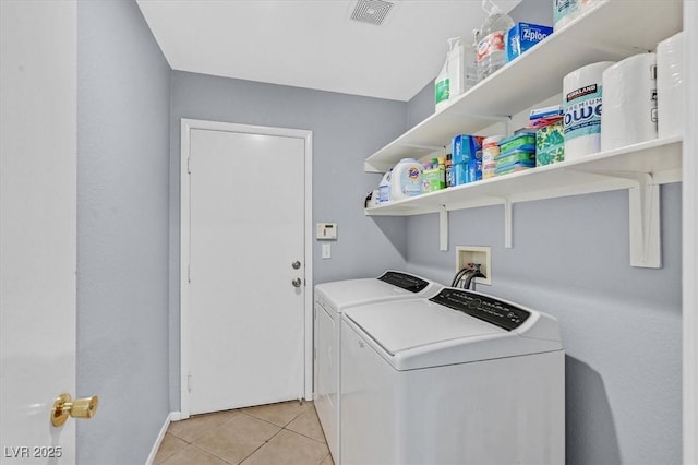 laundry area featuring washing machine and clothes dryer, light tile patterned floors, and baseboards