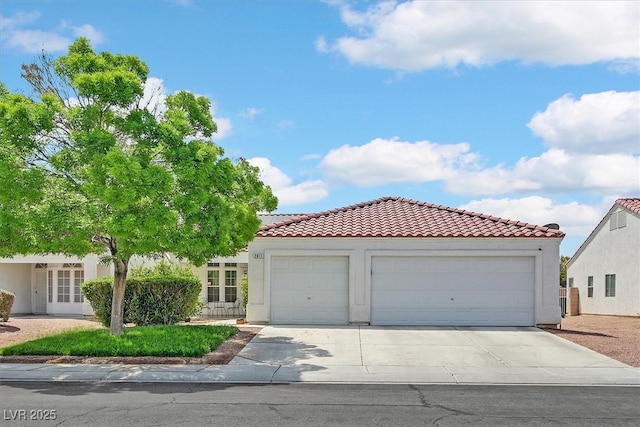 mediterranean / spanish home featuring stucco siding, a tiled roof, concrete driveway, and an attached garage
