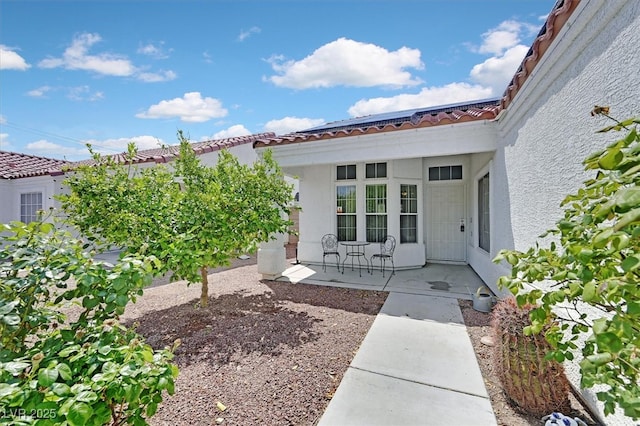 entrance to property featuring a tile roof and stucco siding