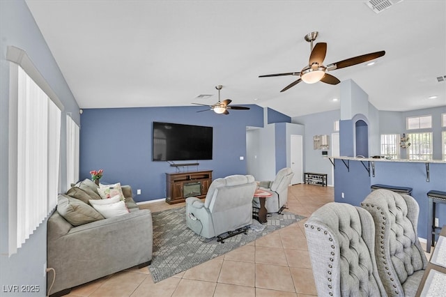 living area featuring lofted ceiling, light tile patterned flooring, a ceiling fan, and baseboards
