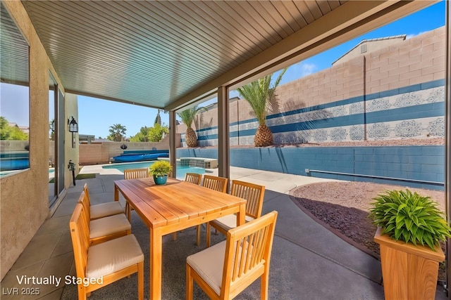 view of patio featuring outdoor dining space, a fenced backyard, and a hot tub